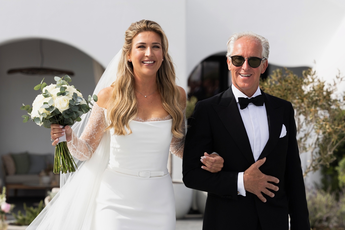 Bo Wilkes wordt naar het altaar begeleid door haar vader – emotioneel moment tijdens exclusieve destination wedding op Santorini