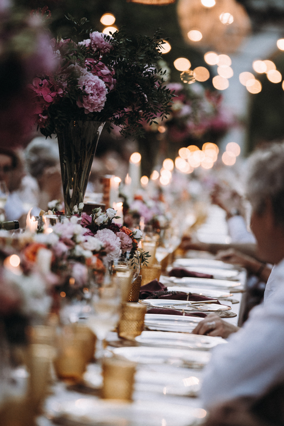 Sfeervol gestylde bruiloftsdiner setting met bloemrijke tafeldecoratie en kaarslicht, georganiseerd door een wedding planner.