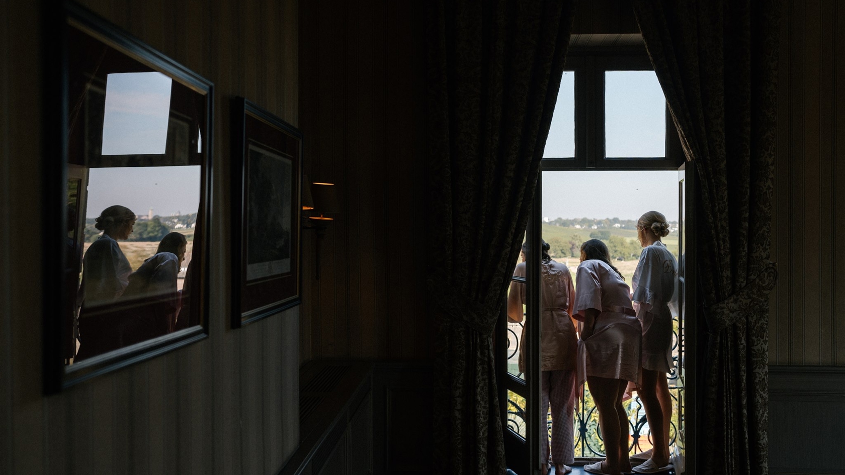 Bridesmaids kijken uit het raam tijdens de bruiloft van Lieselotte & Michiel – een stil moment voorafgaand aan de ceremonie